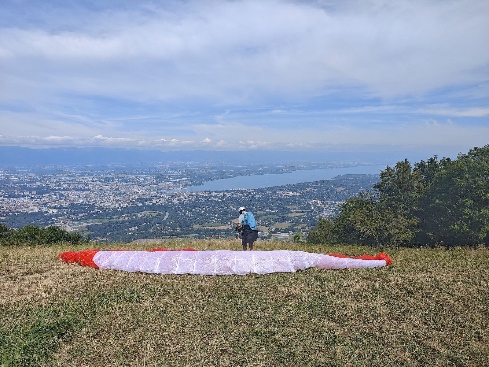 بال پاراگلایدر به شکل کمان روی چمن سکوی پرواز پهن شده است